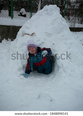 The kid is gets out from the igloo in the winter