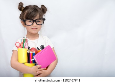 Kid Gets Ready For School. Schoolgirl Holding Many School Supplies: Pens, Notebooks, Scissors And Apple. Back To School Concept. Space For Text, Isolated On White.