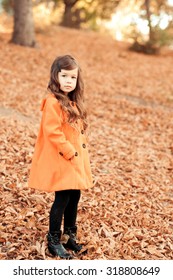 Kid Girl 4-5 Year Old Walking In Park, Wearing Stylish Coat. Looking At Camera. Childhood. Seasonal. 