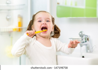 Kid Girl Brushing Teeth In Bathroom