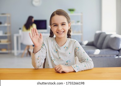 Kid Girl Looking At Web Camera Waving Hand In Living Room