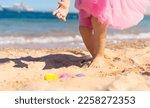 Kid girl on Easter egg hunt on the sandy beach. Happy Easter holidays concept 