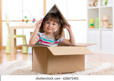 Kid Girl Playing With Book In A Toy House In Children Room.