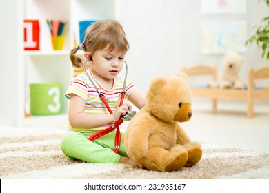 kid girl playing doctor with plush toy at nursery