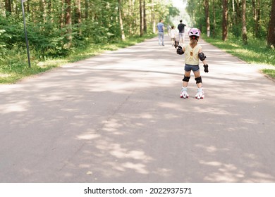 Kid Girl In Protective Sportswear. Little Girl Learning To Roller Skate