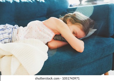 kid girl relaxing at home in weekend morning and sleeping on cozy couch in pajama