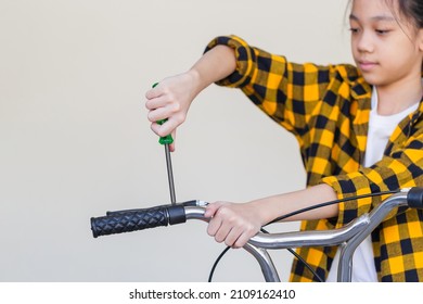 Kid Girl Repairing Her Bicycle At Garage, Little Girl Using A Screwdriver Fixing Bike, Hobby And Repair Concepts