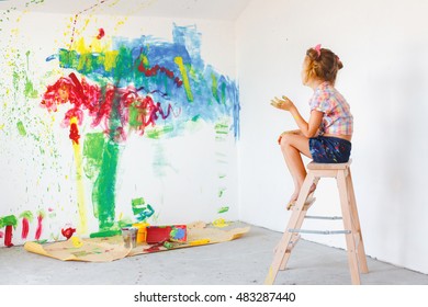 Kid Girl Sitting On A Chair And Looking On Painted Wall