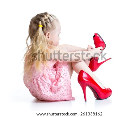 Kid girl trying red mummy shoes on.  Isolated on white
