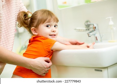Kid Girl Washing Hands With Mom Help In Bathroom