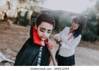 Kid With Halloween Vampire Costume With An Adult Woman Holding A Shovel