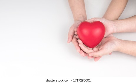 Kid Hand Hold Red Heart On White Background.  Concept Donation Helps Find Loving Health Care Equity And Promote Well Being. Top View.  Copy Space.  International Mother's Day. Gift For You
