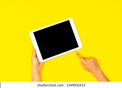 Kid Hand Holding White Tablet Computer And Pointing To Blank Screen On Yellow Background