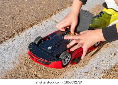 Kid Hand And Red Remote Controlled Car Batteries. 