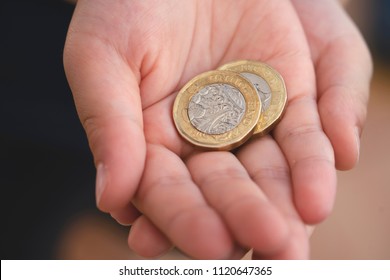 Kid Hand Showing Money Two Pound Coins On His Hands,Child Holding New British One Pound On Both Hands, New Pound Coin, 2017 Design