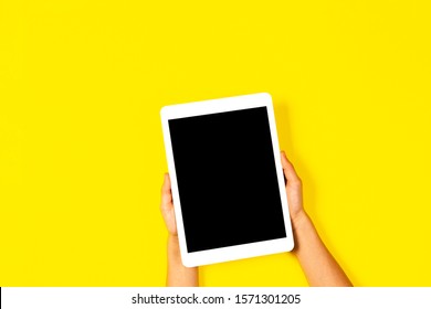 Kid Hands Holding White Tablet Computer On Yellow Background