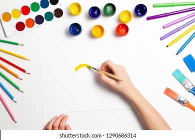 Kid Hands Painting At The Table With Art Supplies, Top View