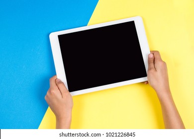 Kid Hands With Tablet Computer On Blue And Yellow Background