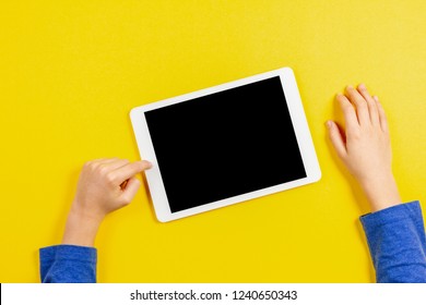 Kid Hands With Tablet Computer On Yellow Background