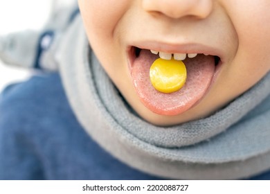 Kid Hold On Tongue Anaesthetic Sore Throat Lozenges For Pain Redness Irritation Treatment.isolated On White Child With Scarf Around Neck.sweet Candy Yellow Color Lemon Honey Ingredients.medicine