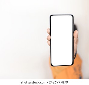 Kid Holding A Mobile with Empty Screen white for placement. Smartphone in the hand of a child showing on front, backdrop with free space on the left side