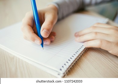 Kid Holding Pen And Writing In Notebook. Close Up.