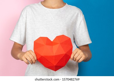 Kid holding red polygonal paper 3d heart in his hands near blue and pink background - Shutterstock ID 1570482769