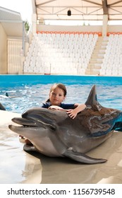 Kid Hugging With Bottlenose Dolphin. Little Girl Embracing Dolphin On Stage. Dolphin Assisted Therapy