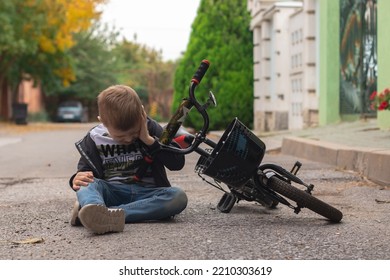 Kid Hurts His Forehead After Falling Off His Bicycle. Child Is Learning To Ride A Bike. The Boy Hit His Head On The Asphalt