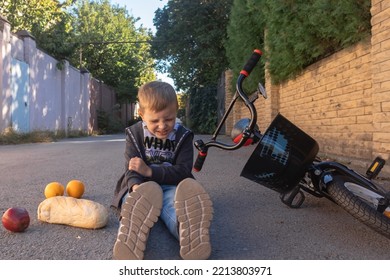 Kid Hurts His Head After Falling Off His Bicycle.when He Fell, He Scattered His Purchases On The Ground. The Boy Hit His Head On The Asphalt