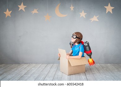 Kid With Jet Pack Looking At Cardboard Stars. Child Playing At Home. Success, Imagination And Innovation Technology Concept