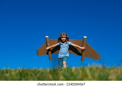 Kid With Jet Pack Superhero. Child Pilot Against Summer Sky Background. Boy With Paper Plane Flight, Toy Airplane With Cardboard Wings, Imagination, Kids Freedom.