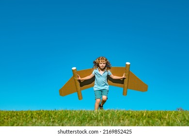 Kid With Jet Pack Superhero. Child Pilot Against Summer Sky Background. Boy With Paper Plane Flight, Toy Airplane With Cardboard Wings, Imagination, Kids Freedom.