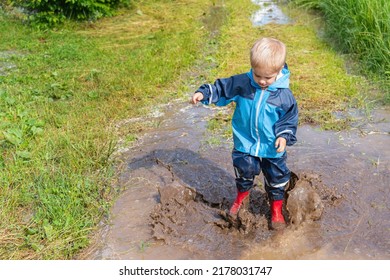 A Kid Jumps Into A Dirty Puddle. After The Rain.