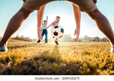 Kid Kicking Football Ball While Playing With His Family - Active Family Having Fun Outdoors Enjoying Leisure Time - Childhood And Happy Lifestyle Concept