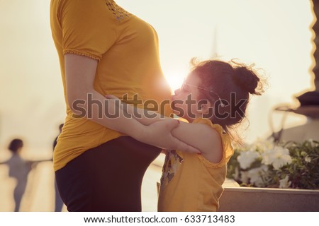 kid kissing the belly of her mom 