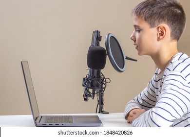 Kid with laptop computer talking into microphone. Techology, online learning, remote education, distance learning at home - Powered by Shutterstock