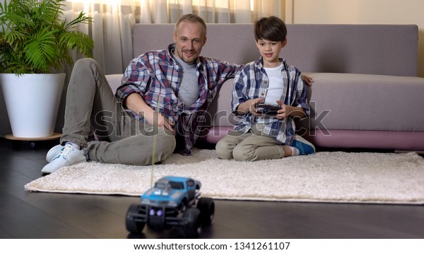 Kid learning to drive car on radio control,\
expensive gift from sunday\
father