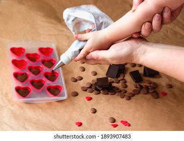 Kid Learning How To Cook In A Cooking Class Together With Mother. Mommy And Me Handmade Valentines Day Dessert. Family Making Chocolate Candy, Hands Filling Heart Shaped Mold From Pastry Bag