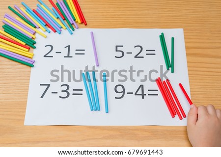 kid learning simple subtraction by counting numbers of sticks