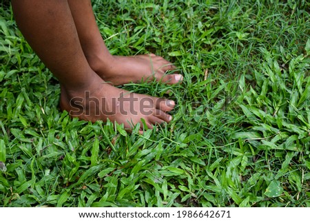 Kid leg on a green grass. Brown Feet of a young little boy on a grass 