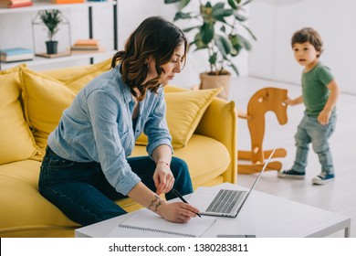 Kid Looking How Mother Working With Laptop In Living Room