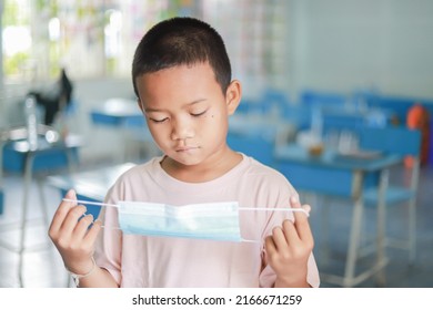 Kid Looking At Mask With Bored Feeling Of Wearing Mask In Daily Life