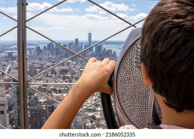 A kid is looking New York landscape through the coin operated binoculars from the 86th floor of the Empire State Building