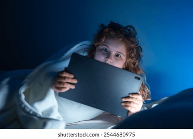 Kid lying on bed and surfing Internet on tablet in dark room. Boy reading Tablet in bed at night. Kid in pajamas using tablet before going to bed. Kid using tablet gadgets. - Powered by Shutterstock