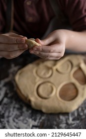 Kid Making Pelmeni (meet Dumplings) Of Dough On Wooden Table With Ingredients Flour, Oil, Salt, Dark Background. Copy Space. Home Bakery Concept, Kitchen Cooking Story.