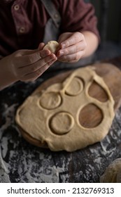 Kid Making Pelmeni (meet Dumplings) Of Dough On Wooden Table With Ingredients Flour, Oil, Salt, Dark Background. Copy Space. Home Bakery Concept, Kitchen Cooking Story.