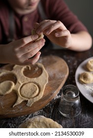 Kid Making Pelmeni (meet Dumplings) Of Dough On Wooden Table With Ingredients Flour, Oil, Salt, Dark Background. Copy Space. Home Bakery Concept, Kitchen Cooking Story.