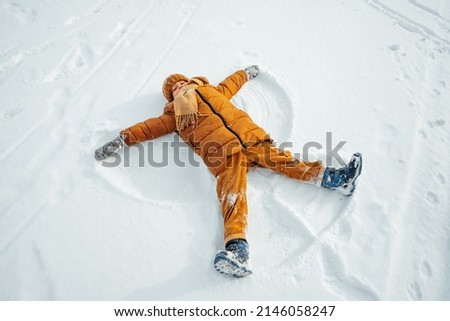 Kid making a snow angel in winter park