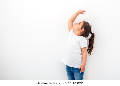 Kid Is Measuring The Growth On The Background Of Wall.